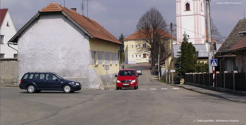 Neoznačená křižovatka v obci, zleva modré kombi, uprostřed proti kameře červené auto